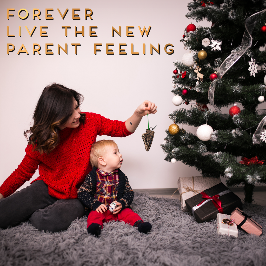 mom and baby boy decorating the tree Christmas tradition with new ornament